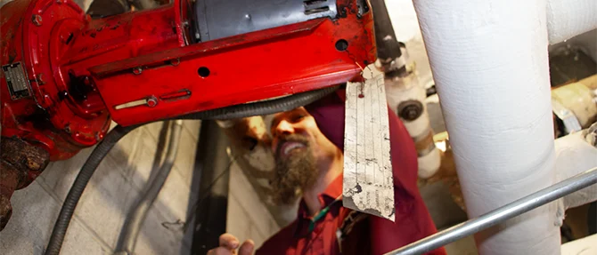 Technician installing boiler piping and circulation pump during professional boiler installation