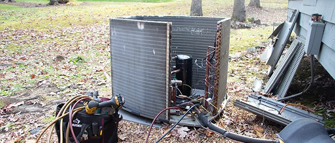 Outdoor air conditioning unit with panels removed for HVAC repair and maintenance.