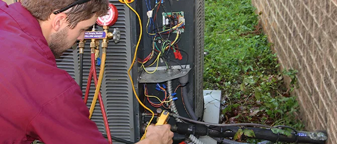 HVAC technician inspecting and servicing the electrical components of an outdoor air conditioning unit.