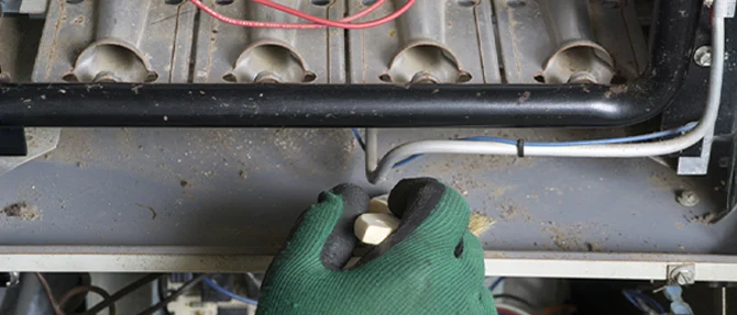 Technicians gloved hands inspecting the interior of a furnace burner assembly