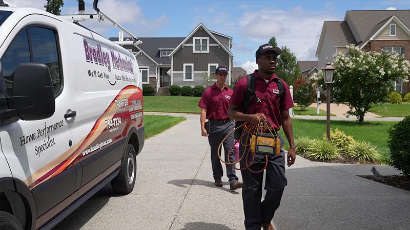 BM technicians walking toward a home with tools. Van perked on the driveway
