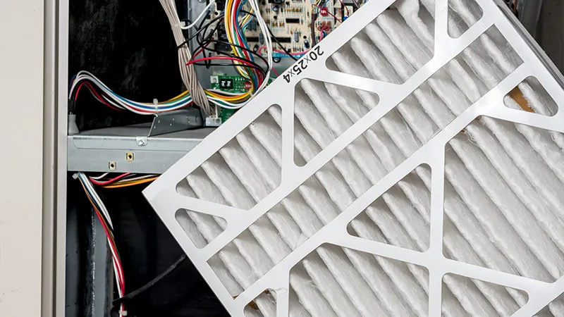 Technician replacing furnace air filter during electric heating system service inspection