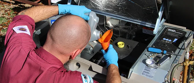 Technician wearing gloves pouring oil into an open standby generator using a funnel during maintenance service outside a residential home