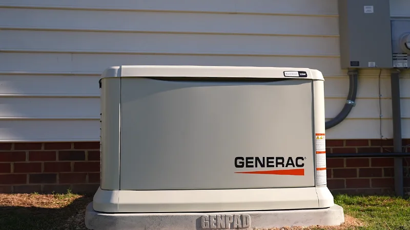 Generac standby generator installed outside a residential home near siding wall in warm sunlight