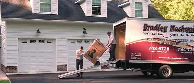 Technicians unloading a new heat pump unit from a Bradley Mechanical truck at residential home