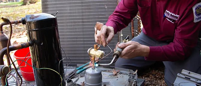 HVAC technician soldering copper lines during a heat pump repair