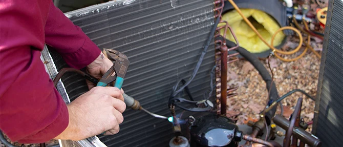 Technician using a tool to repair an HVAC unit.