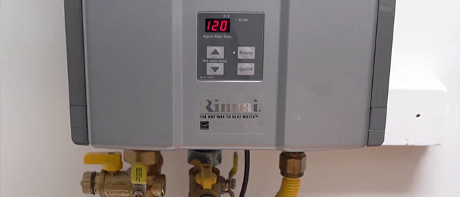 Rinnai tankless water heater with digital temperature display and connected plumbing valves.