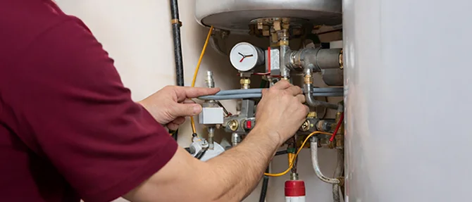 Professional adjusting valves and pipes during water heater repair with pressure gauge visible
