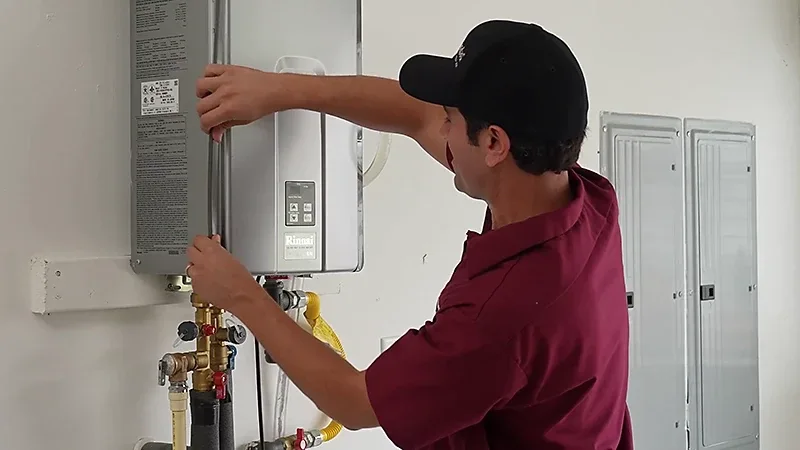 Technician installing or servicing a wall-mounted gas tankless water heater unit.